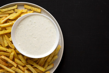 Homemade Crispy Ranch Fries on black surface, top view. Flat lay, overhead, from above. Copy space.