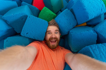 Fitness, fun, leisure and sport activity concept - Funny man taking selfie on a trampoline indoors