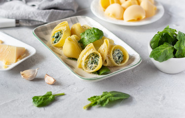 Italian pasta lumaconi stuffed with spinach and ricotta cheese, sprinkled with grated parmesan. Horizontal orientation