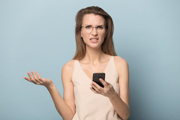 Fototapeta premium Confused woman in glasses hold cellphone having connection problems