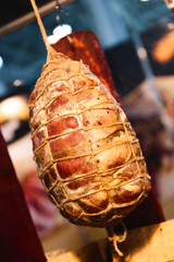 A piece of ham hangs in a rope net. A delicious, beautiful piece of smoked meat