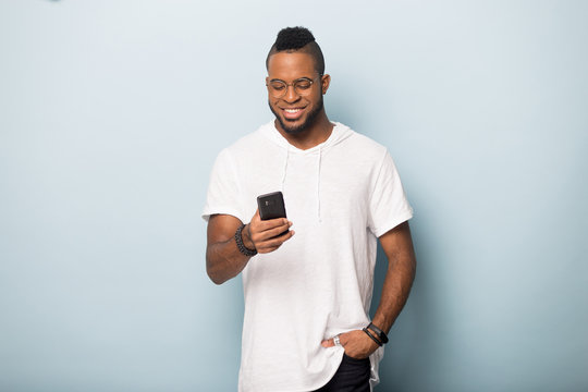 Smiling Black Male Isolated In Studio Using Cellphone Texting