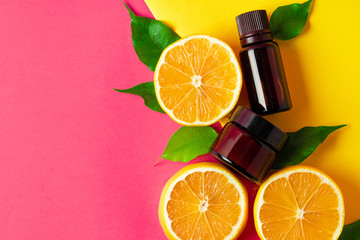 Citrus essential oil. Sliced citrus fruit and aroma bottles on pink background