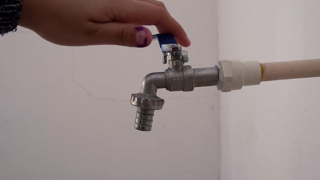 Humano abriendo la llave de agua en el fregadero