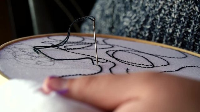 Mano femenina bordando textura abstracta sobre tela blanca