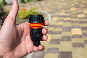 Fototapeta premium Connector in the male hand for a watering hose at the dacha. Close-up.
