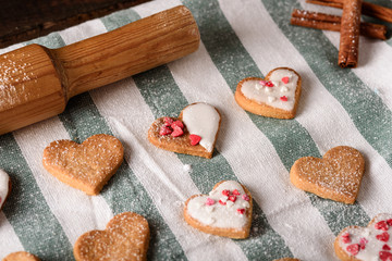 homemade glazed cookies hearts on white and green cloth towel with rolling pin and cinnamon sticks