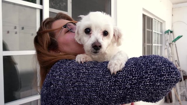 Joven rubia carga en brazos a su peque&ntilde;o perro blanco