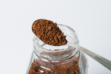 Instant coffee granules in a spoon, macro, on white background