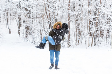 Young couple in love have fun in the snowy forest. Active winter holidays.