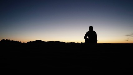 Fototapeta na wymiar Mann genießt Sonnenuntergang in der Wüste