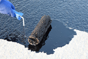 Worker applies bitumen mastic on the foundation