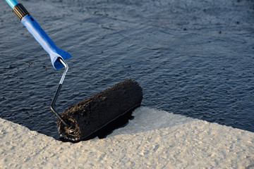 Worker applies bitumen mastic on the foundation