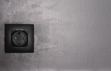 Minimal black in home interior. Copy space. Conceptual trendy electric socket on black matte wall.