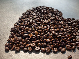 Valentines Day card - black coffee heart-shaped beans on the surface of a wooden table.