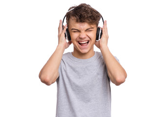 Happy teen boy with headphones, isolated on white background. Cheerful child listening to music and singing song. Emotional portrait of handsome teenager guy enjoying music.