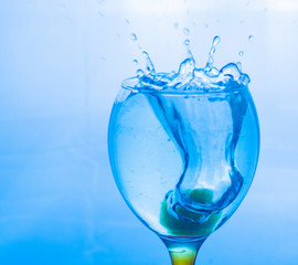 splashing water in a glass. splashes in blue shades. ice in a glass. blue drink