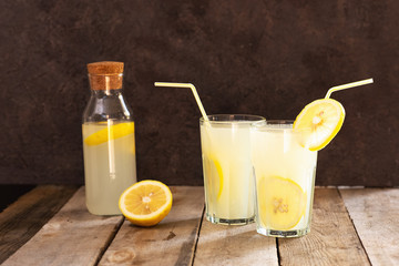Preparation of the lemonade drink. Lemonade in the jug and lemons with mint on the table outdoor