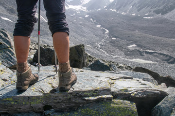 Hiker’s legs and trekking poles in alpine landscape.