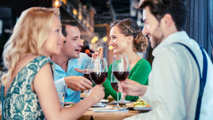 People in a restaurant eating and drinking red wine