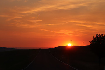 Wind turbines with a bright orange sunrise
