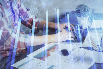 Double exposure of stock graph with businessman typing on computer in office on background. Concept of hard work.