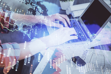 Double exposure of stock graph with businessman typing on computer in office on background. Concept of hard work.