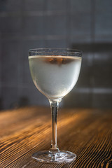 Transparent cocktail served on the wooden bar desk decorated with dried tropical flower