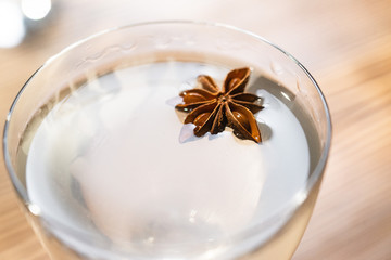 Transparent cocktail served on the wooden bar desk decorated with dried tropical flower