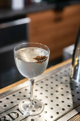 Transparent cocktail served on the wooden bar desk decorated with dried tropical flower