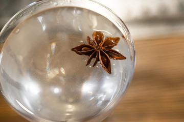 Transparent cocktail served on the wooden bar desk decorated with dried tropical flower