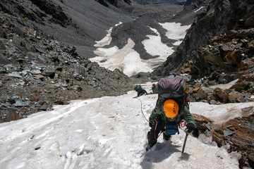 Group of mountain climbers climbs a steep pass.