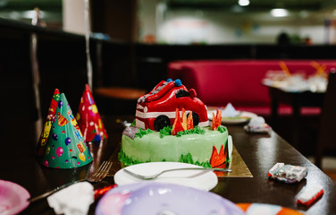 Festive baby cake with fire truck on the decorated table for child birthday celebration.  The concept kids party. The boy's birthday is 3 years. Close-up.