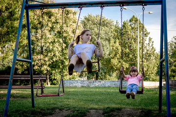 Little girls swinging while playing outdoors.