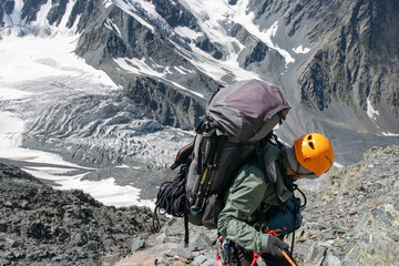 A mountain climber climbs down from the pass by the rope.