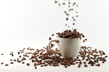 coffee beans poured into a mug with beans isolated on white