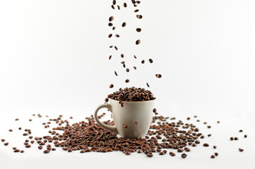 coffee beans poured into a mug with beans isolated on white