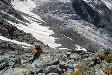 A mountain climber climbs down from the pass by the rope.