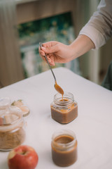 Homemade salty brown liquid caramel. Homemade soft caramel made from sugar on a background of apples and pumpkins