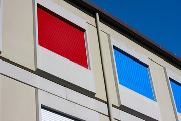 Window shades in bright colors with bright blue sky in the background of the building.
