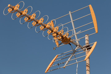 close up of television antenna on a rooftop in front of blue sky