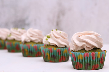 A row of spinach-mint cupcakes with fruit jam and berry cream on top
