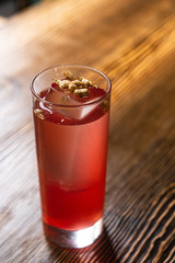 Pink and red Fresh colorful exotic alcoholic cocktail with lemon and ice in the bar. Colorful pink Soft drink with ice and decorated with dried flowers on the bar desk. Red colorful Mojito