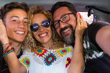 group of three people together in the car having fun and taking a selfie - happy family looking at the camera