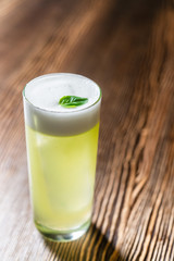 Green cocktail on bar counter. Drink with martini, gin, rum, tequila with alcohol and white foam on...