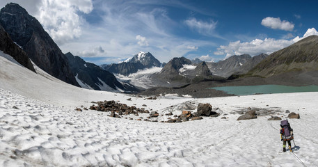 A mountain climber climb down the mountain pass on the background of beautiful alpine landscape.