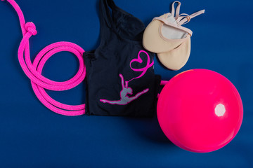 Rythmic Qymnastic equipment. Pink Skipping Rope, Sasaki ball, gymnastic shoesand leothard. Isolated on blue background