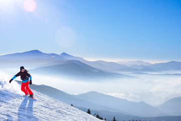 Snowboarder Riding Snowboard on the Slope in the Morning Mountains at Sunny Weather. Snowboarding and Winter Sports