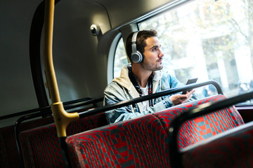 A boy listens to music in headphones and uses the mobile phone on a bus