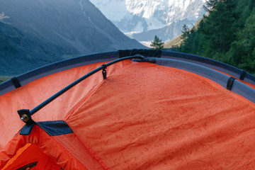 After the rain. Orange tent with rain drops on the background of alpine landscape.. © Kirill